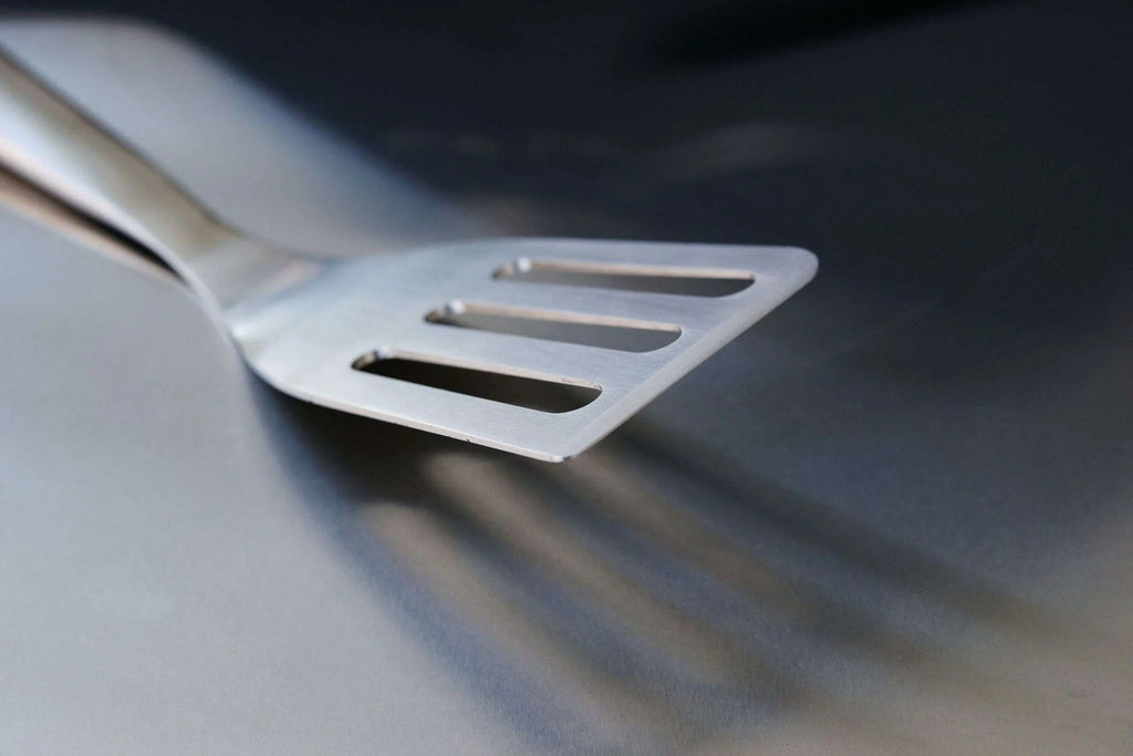 Spatule en acier inoxydable avec design fendu pour griller et servir.