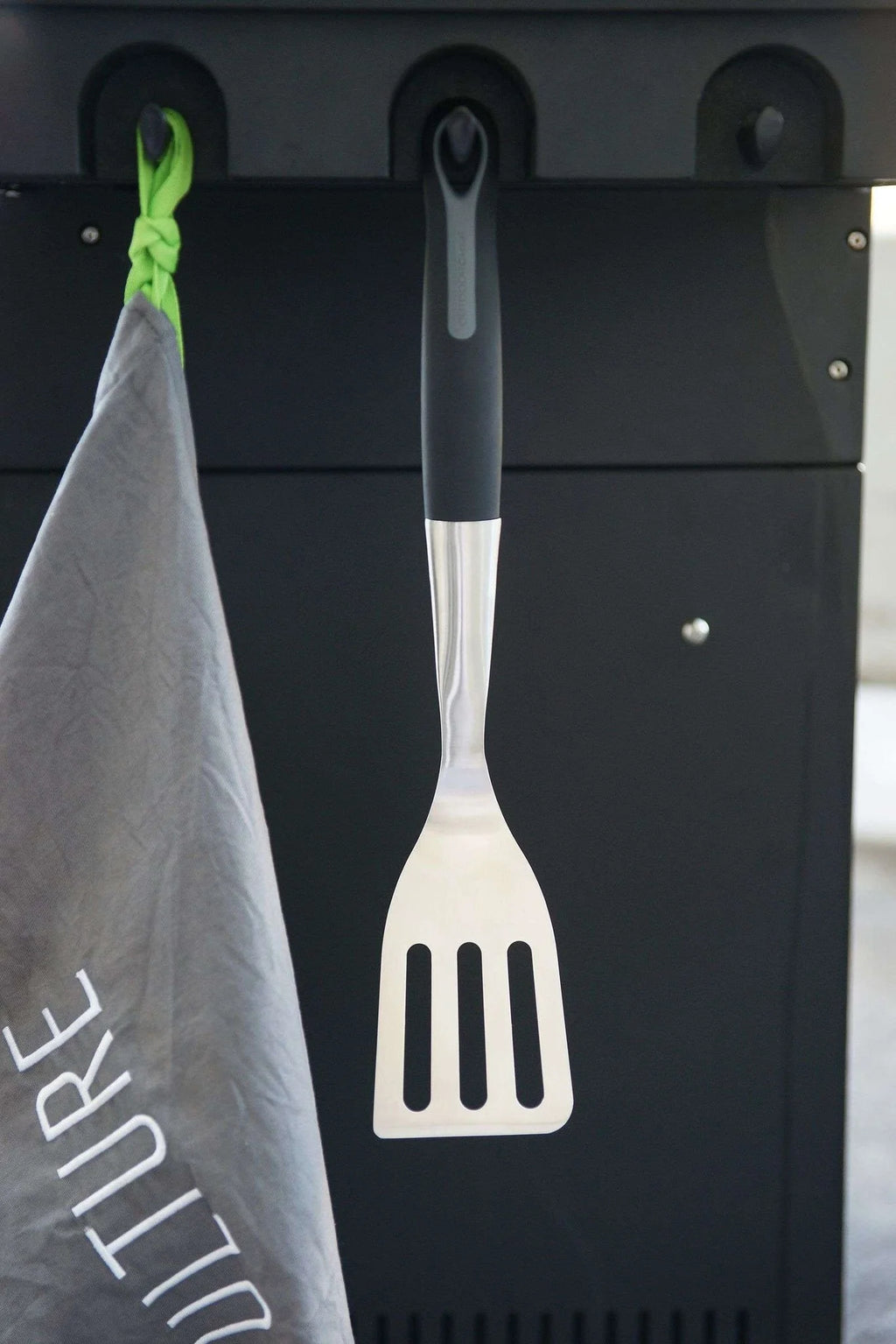 Spatule avec manche noir et tête en plastique blanc, probablement en silicone ou en caoutchouc pour la résistance à la chaleur.