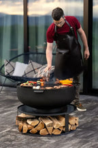 Autocuiseur en fonte noire avec poignées en bois et un couvercle, conçu pour la cuisson en extérieur.