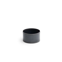Contenant cylindrique noir mat avec une surface lisse et des bords arrondis.