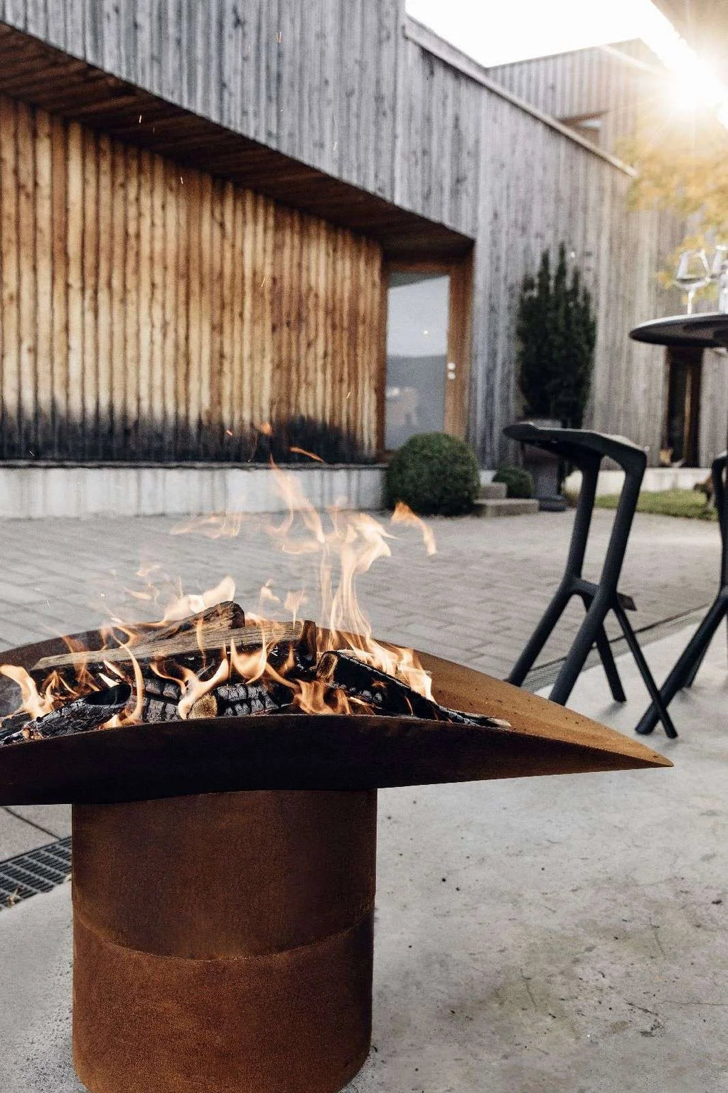 Foyer de feu en métal rouillé avec un design triangulaire et des pieds noirs.