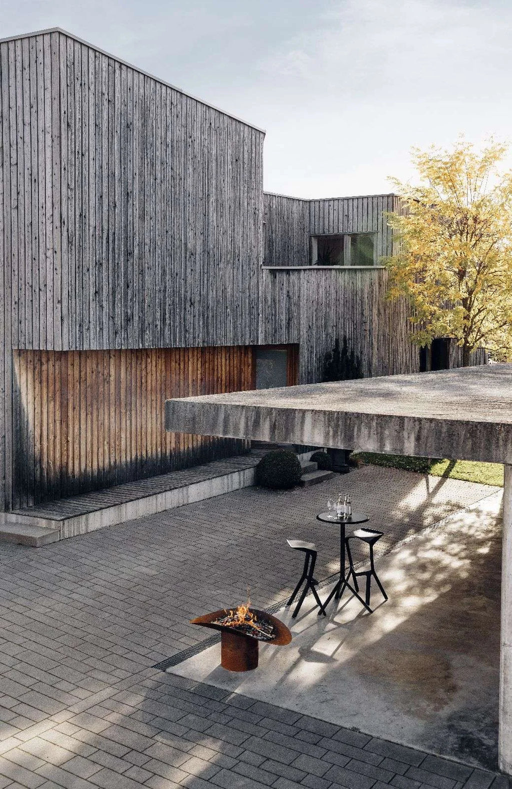 Maison en bois moderne avec toit courbé et terrasse en briques.