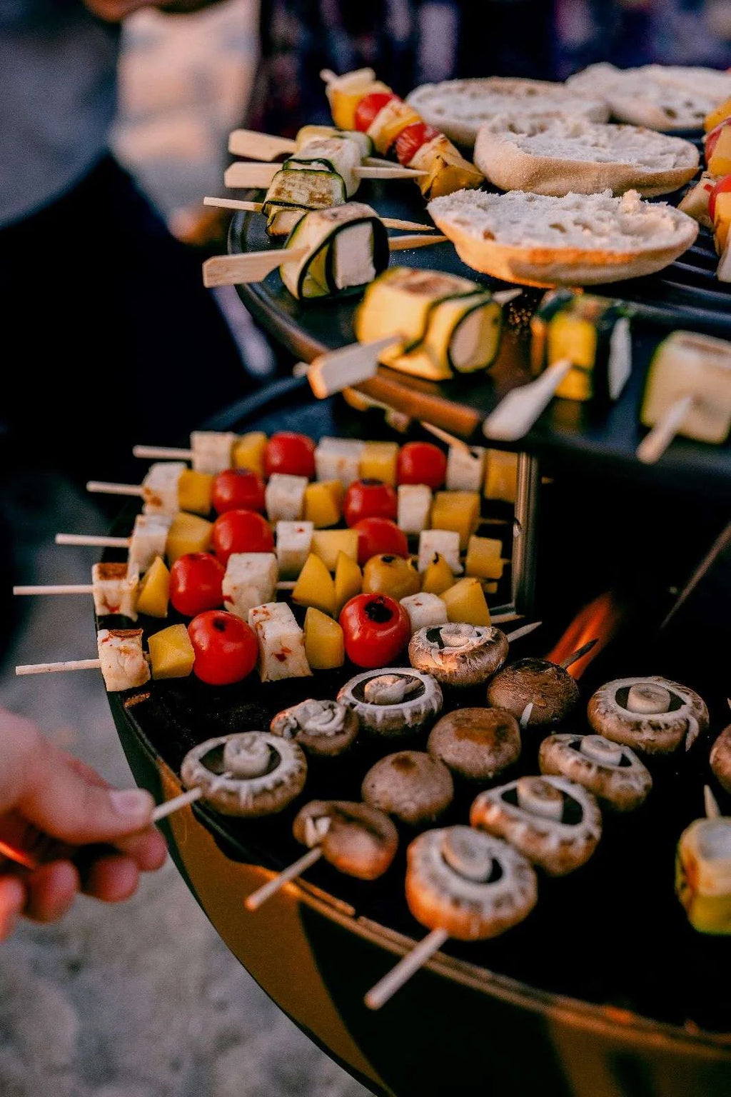 Gril de barbecue avec brochettes et champignons, tomates, tranches de fromage, rondelles de pain et légumes dessus.