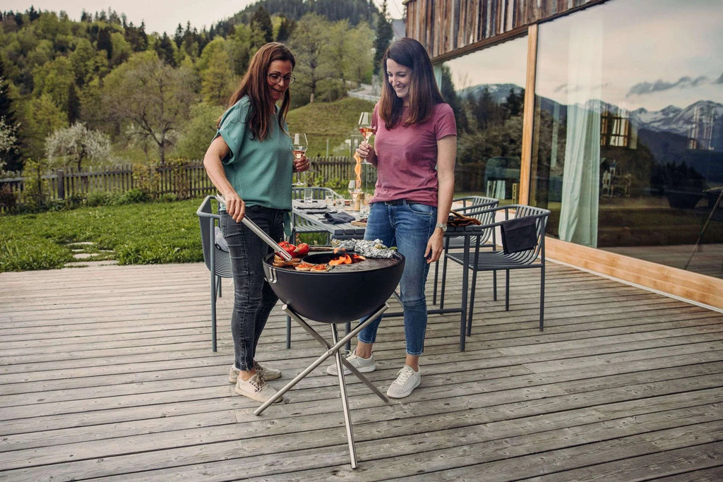 Barbecue au charbon avec un bol noir et des pieds en argent.