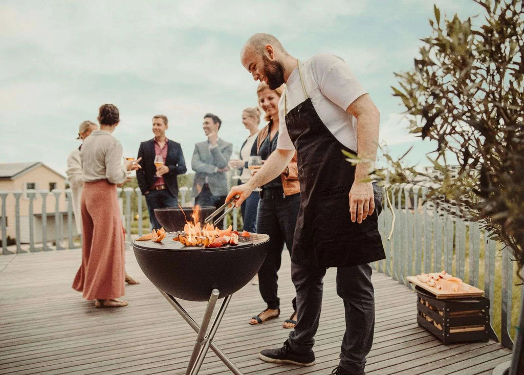 Barbecue au charbon avec support métallique et couvercle, corps noir, pieds argentés.