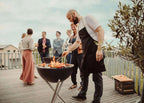 Barbecue au charbon avec support métallique et couvercle, corps noir, pieds argentés.