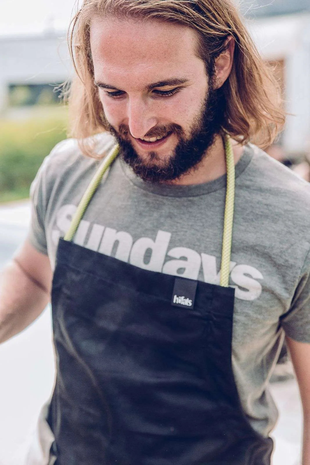 Tablier en cuir noir avec bretelles jaunes et logo ’hills’.