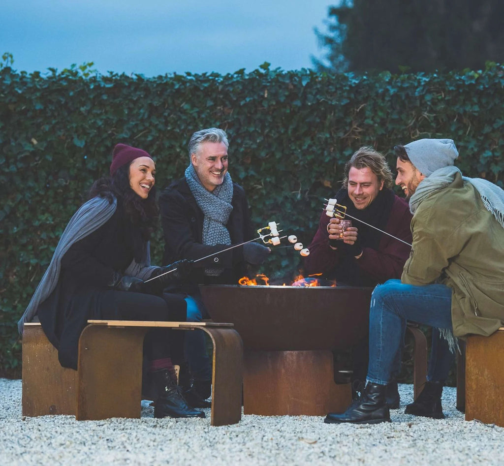 Fosse de feu avec bancs en bois et tiges métalliques pour faire griller des guimauves.