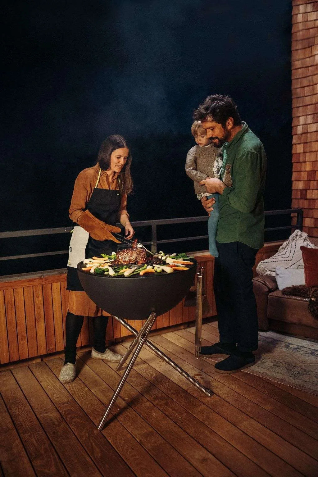 Barbecue au charbon avec un design noir et rond et des pieds en métal robustes.