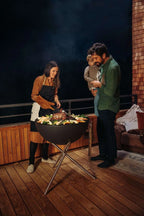 Barbecue au charbon avec un design noir et rond et des pieds en métal robustes.