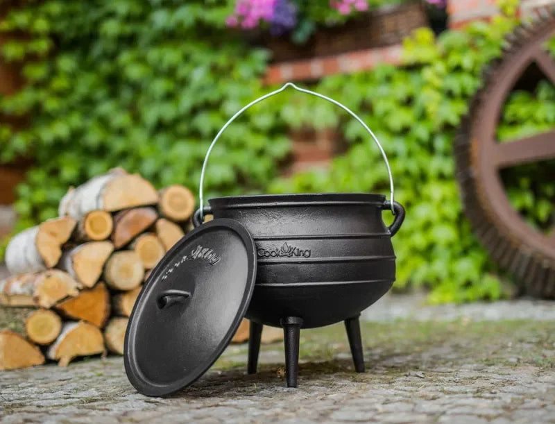 Chaudron en fonte noire avec couvercle et poignée, conçu pour la cuisson en extérieur.