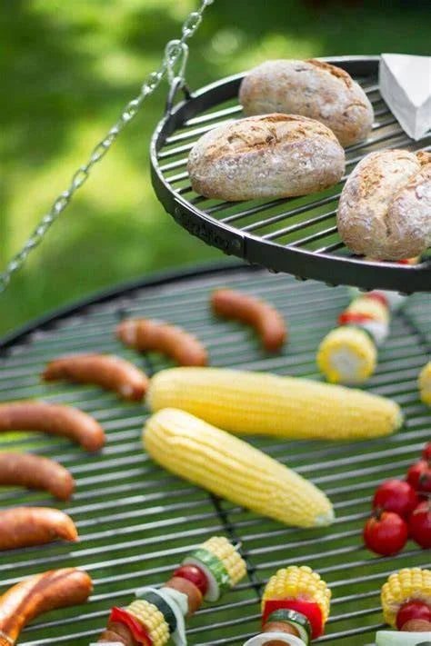 Gril de barbecue avec diverses viandes et légumes en train de cuire dessus.