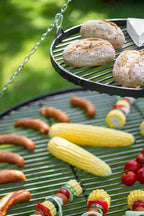 Gril de barbecue avec diverses viandes et légumes en train de cuire dessus.