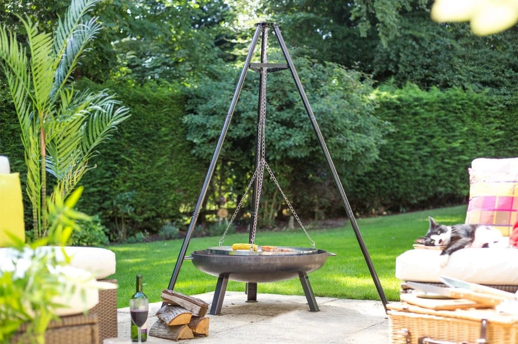 Foyer de feu sur trépied en métal noir avec chaînes suspendues et bol de cuisson rond