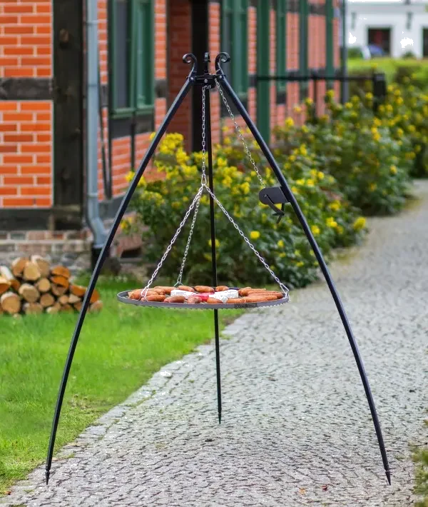 Gril suspendu en fer forgé avec maillons de chaîne et brochettes en bois pour la cuisine en extérieur.