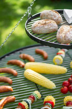 Gril de barbecue avec diverses viandes et légumes en train de cuire dessus.